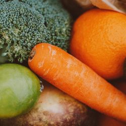 A vibrant collection of fresh vegetables and fruits including carrots, broccoli, and oranges.