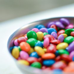 Vibrant close-up of assorted candy-coated chocolates in a silver bowl.